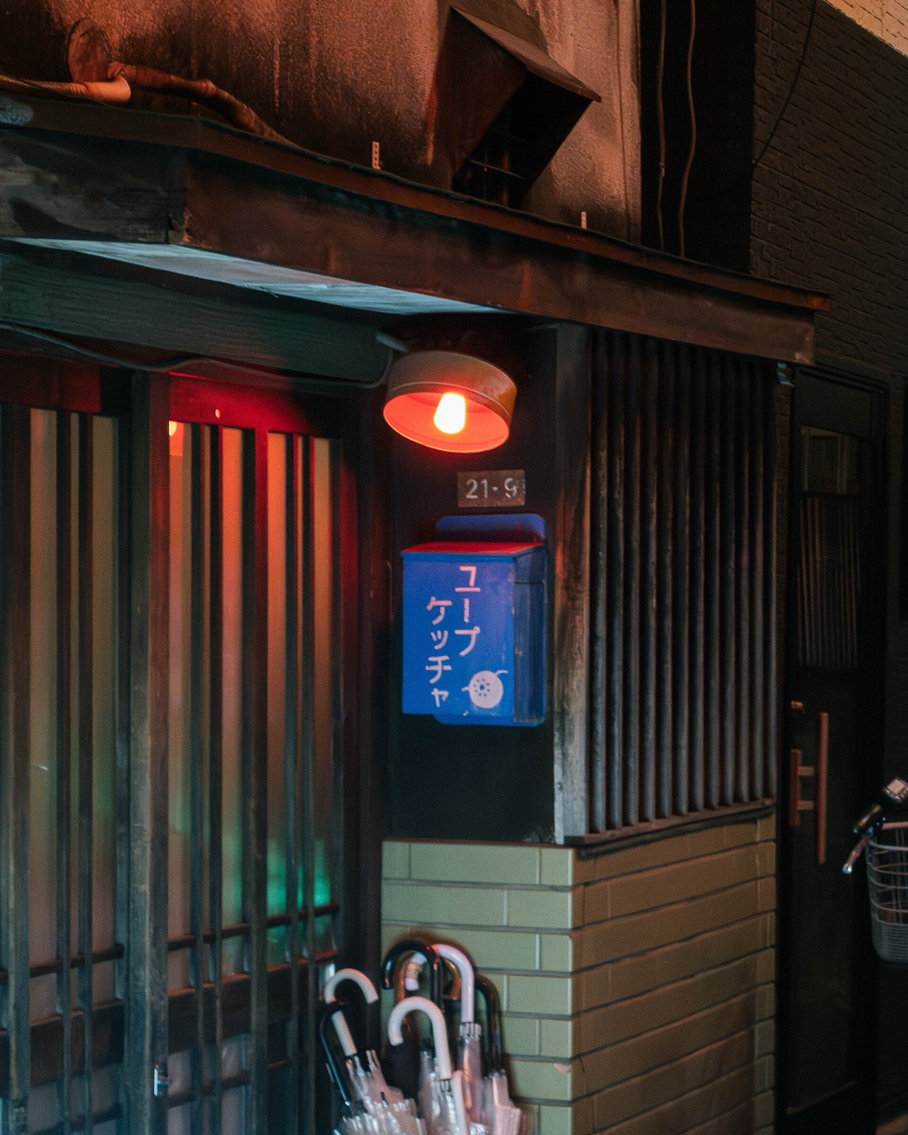 Väikese baari uks Tokyos öösel, punane lamp ja käsitsi maalitud silt